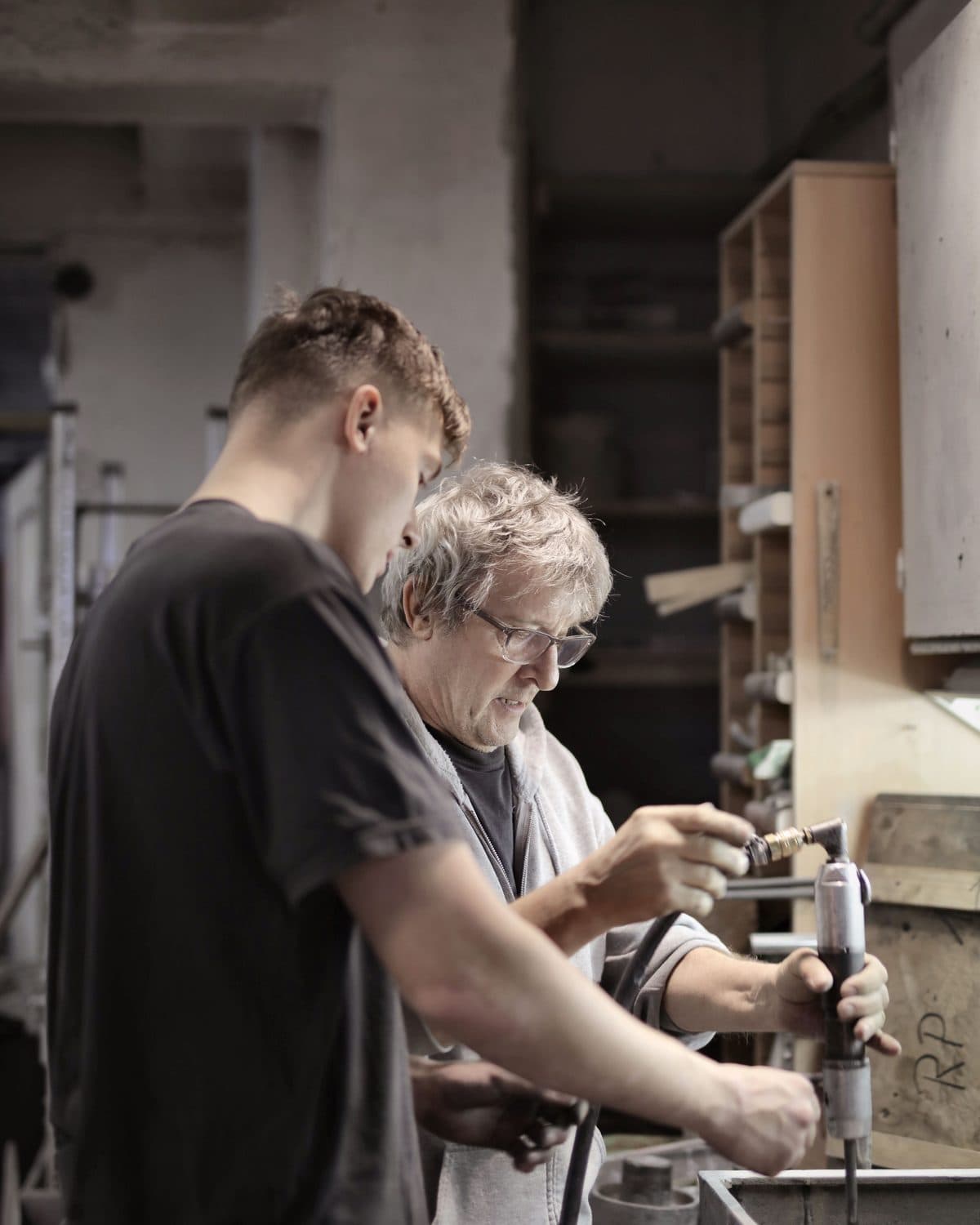 Un operario veterano y un joven trabajan juntos en una máquina de un taller